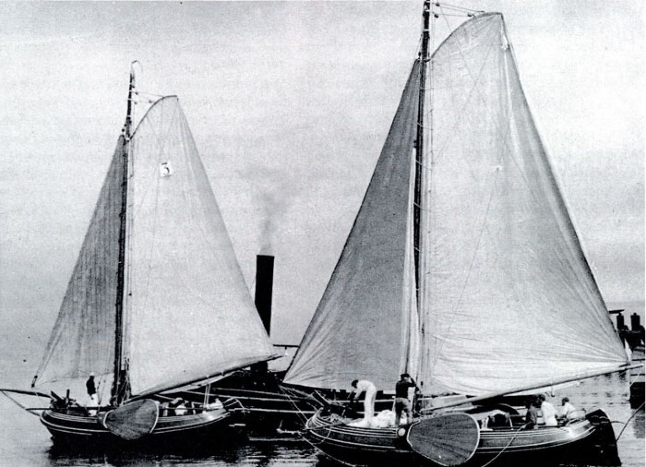 De boeiers "Mimi" van P.C. Andreae (huidige "Pleuntje") (I.) en "Johanna" van R.H.S. Visser (huidige "Rana"?) (r.) verlaten de haven van Harlingen voor een zeilwedstrijd, 1912 (Coll FSM)