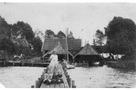 Links de werf van Visser en rechts de werf van Helder aan het Paterswoldsemeer. Aan de steiger het klipperachtige scheepje “Neerlandia” in het botenhuis links van de dame op de steiger de “Poseidon” van Jan te Siepe. Foto na 1910. (Collectie GtC) 